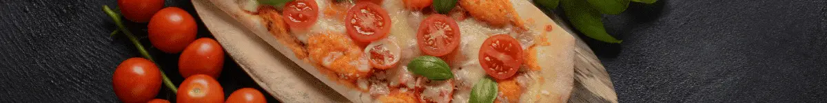 A pizza made with fresh red and yellow tomatoes and basil from a pizza garden.